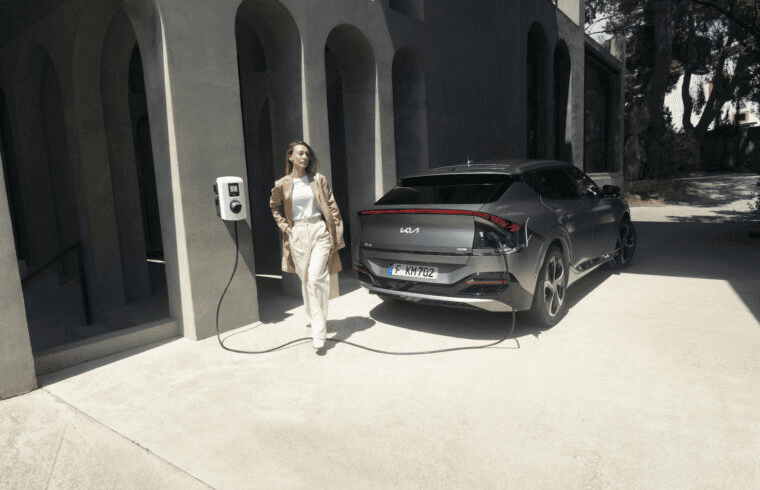 Sieviete pie elektroauto uzlādes stacijas