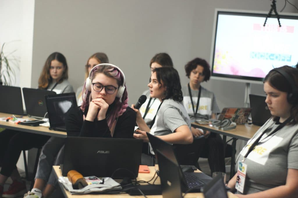 Meitenes sēž pie galda